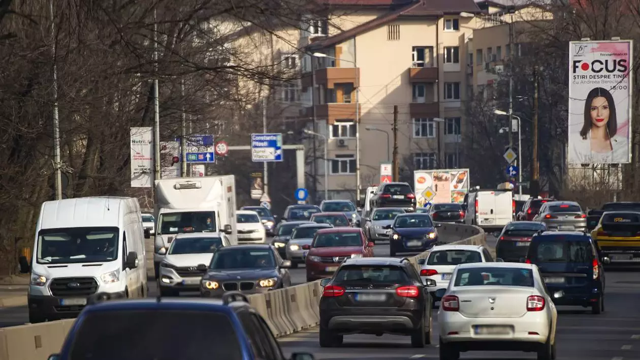mai multe masini aflate in trafic pe un drum cu trei benzi pe sens. se observa masinile din ambele sensuri si cateva indicatoare rutiere