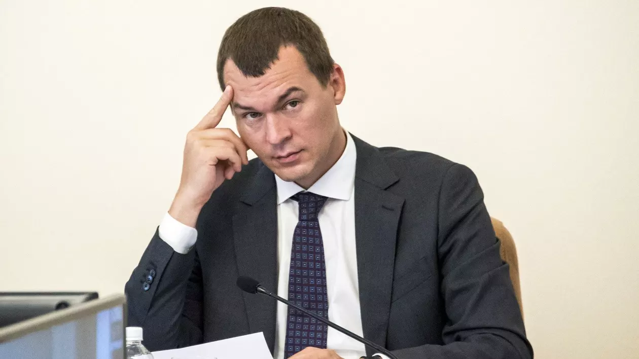 Mihail Degteariov surprins în timp ce-și duce una dintre mâini la frunte. Este îmbrăcat într-un costum negru, cu cămașă albă și are o cravată cu model