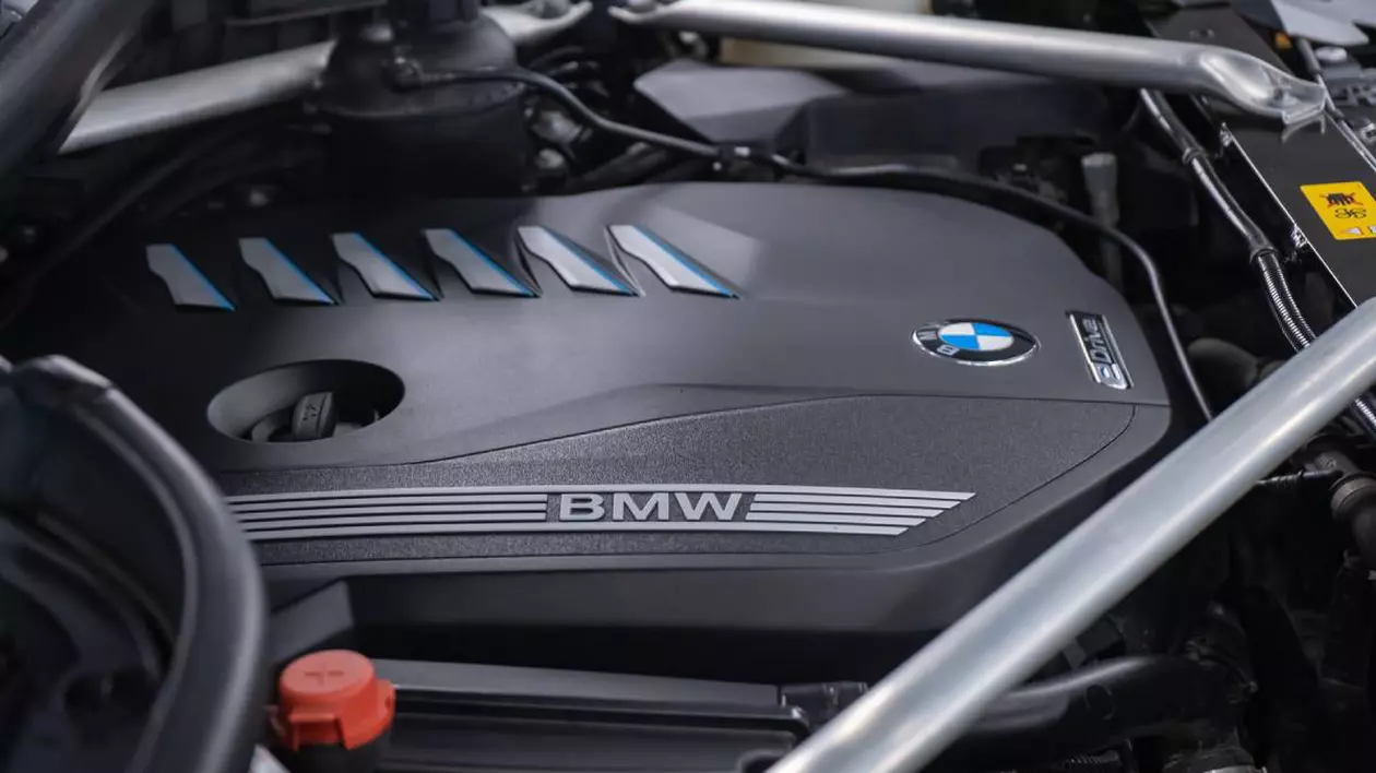 compartimentul motor al unei masini bmw. se observa capacul inscriptionat cu sigla auto bmw