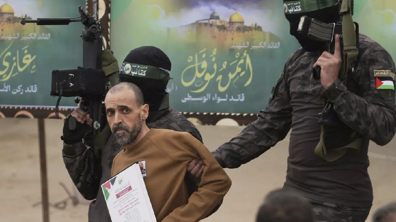 Prizonierul israelian Eli Sharabi, ținut ostatic de Hamas în Gaza din 7 octombrie 2023, este escortat de luptători Hamas înainte de a fi predat Crucii Roșii în Deir al-Balah, centrul Fâșiei Gaza, 8 februarie 2025.
