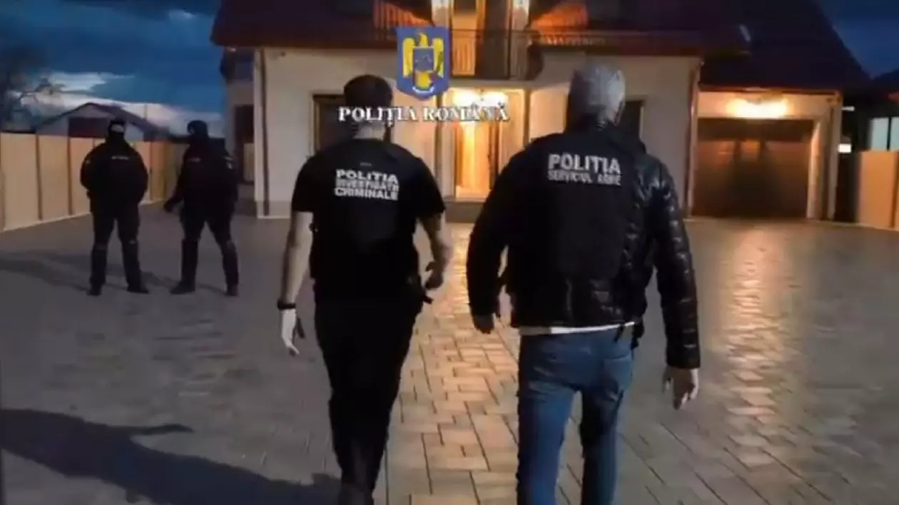 Polițiști și mascați în timpul unor descinderi în curtea unei case, noaptea
