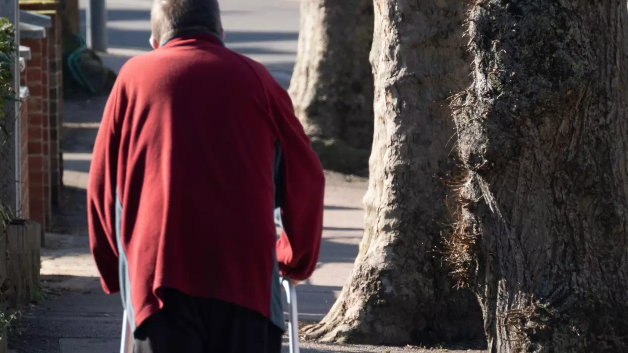 Persoană care se deplasează cu un cadru de mers