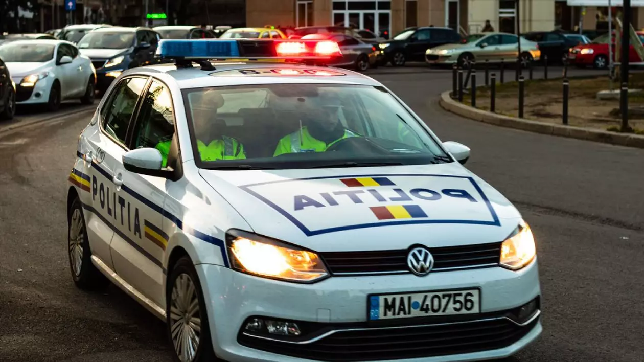 Mașină de Poliție, cu girofarul pornit, pe o stradă din București, cu doi polițiști în interior