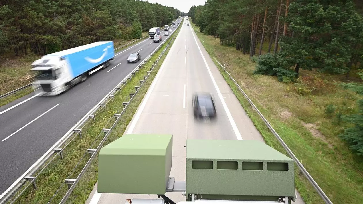 Un dispozitiv de recunoaștere a plăcuțelor de înmatriculare (KESY) este montat sub balustrada unui mic pod peste o autostrada în Germania