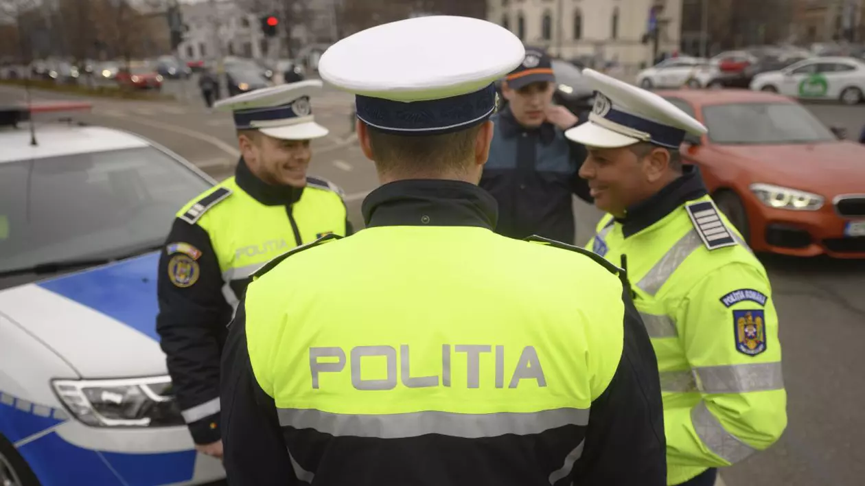 Trei polițiști, îmbrăcați în uniformă, în timp ce discută lângă o autospecială de Poliție, pe o stradă din București