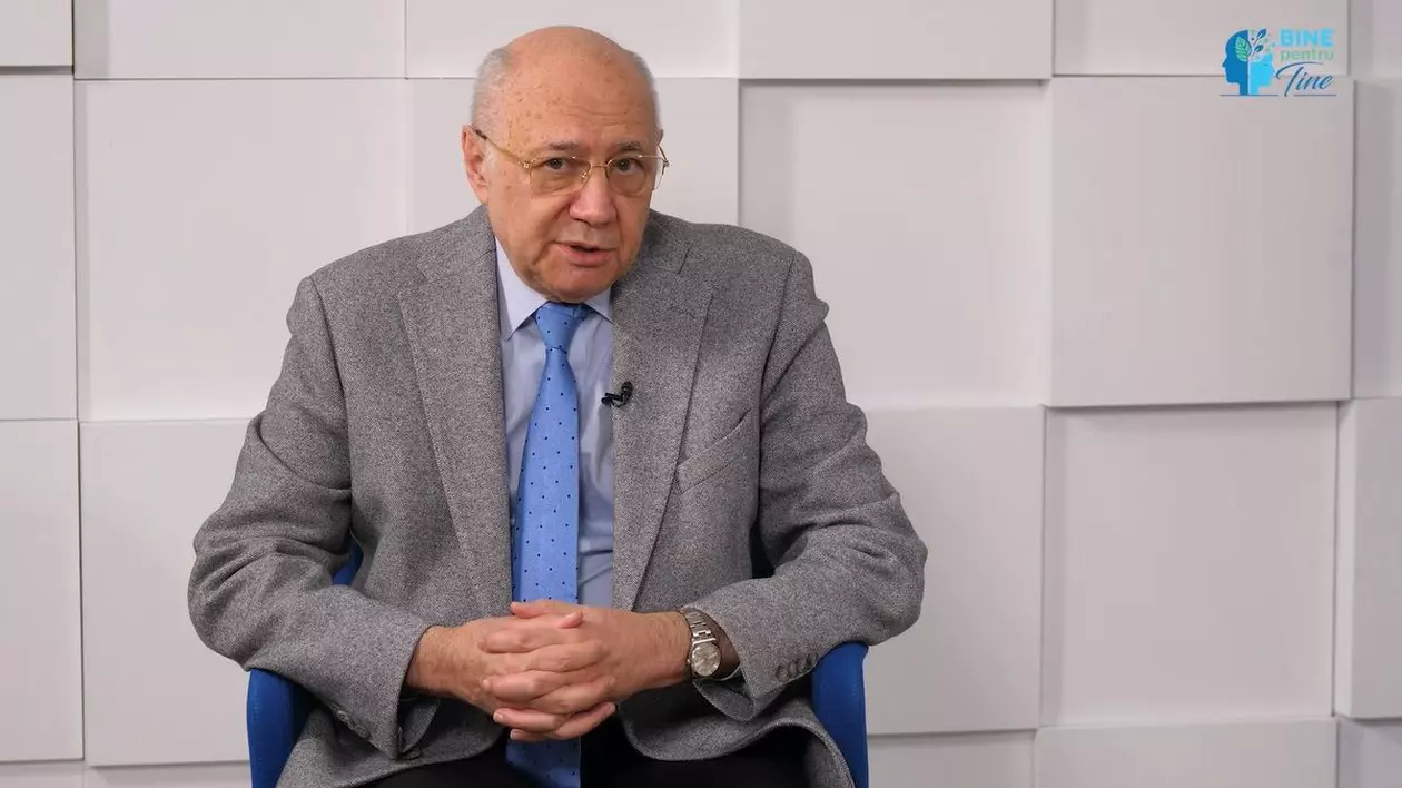 Profesorul dr. Irinel Popescu, în studioul emisiunii Bine pentru Tine, îmbrăcat într-un costum gri, cu o cămașă albă și o cravată de culoare albastră