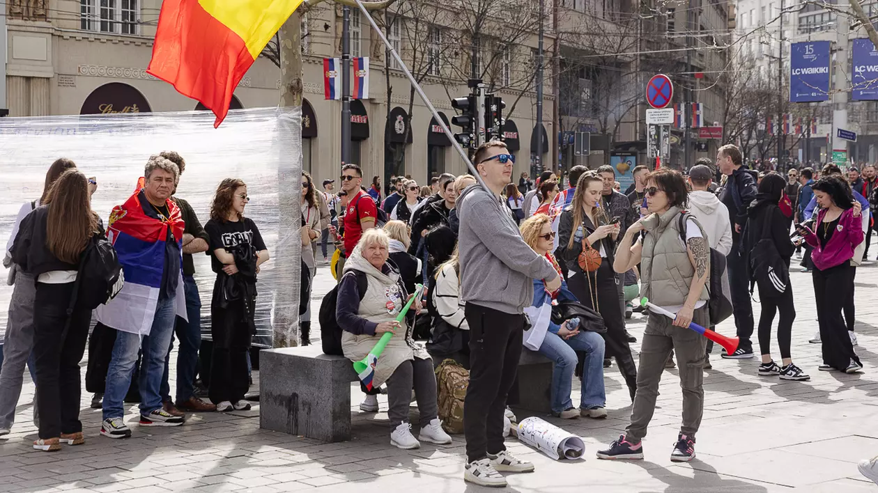 Mai mulți protestari la protestul din Belgrad, Serbia, pe 15 martie. Unul dintre aceștia țin steagul României.