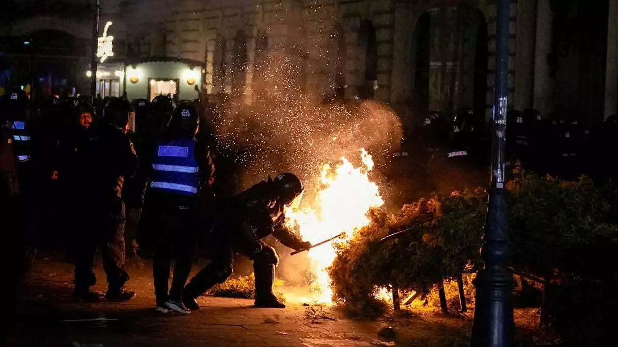 Mai mulți bărbați intervin pentru a stinge un incendiu in Centrul Vechi din București, în timpul unui protest, pe 9 martie 2025.