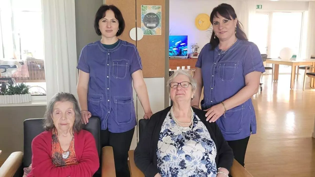 Două dintre româncele care au mers la un stagiu de practică pentru îngrijirea bătrânilor în Belgia, alături de două femei în vârstă, într-o cameră a centrului