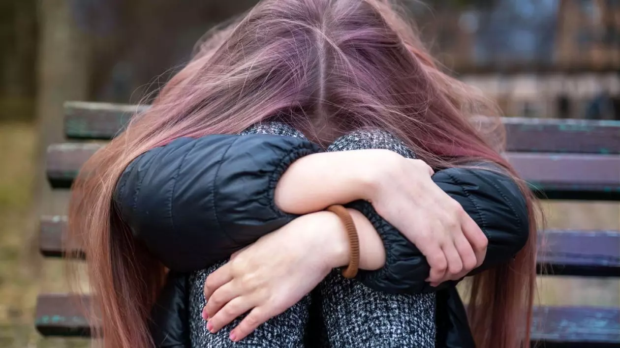 Tânără deprimată tristă stând pe o bancă într-un parc