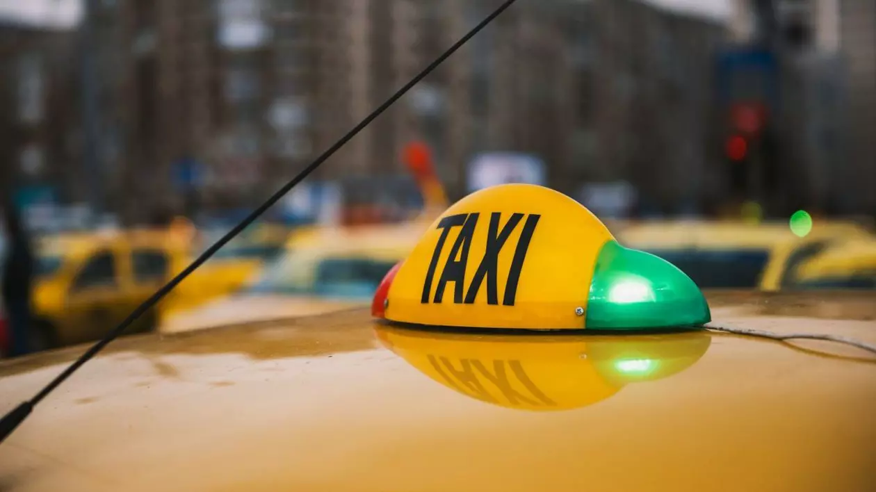 Plafonul unei mașini galbene de taxe pe care se vede firma și becul verde aprins