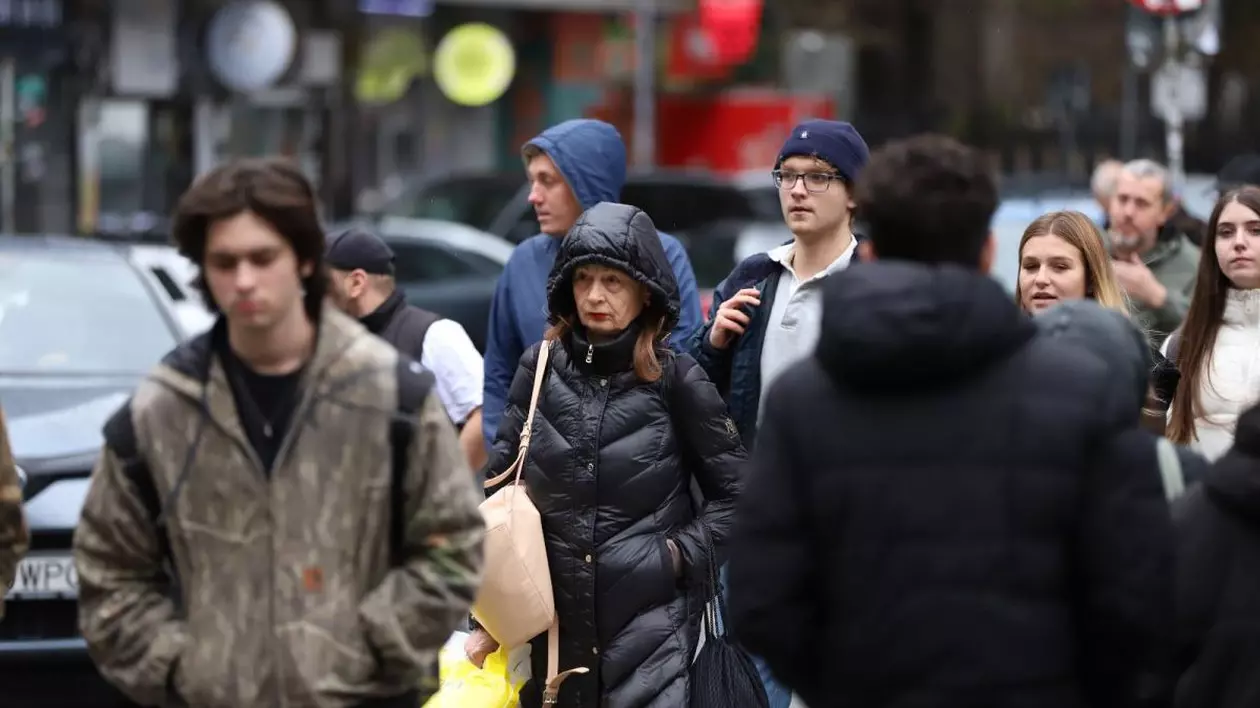 Mai mulți oameni merg pe stradă în București și poartă căciuli sau glugă, după ce meteorologii au anunțat ploi și vânt