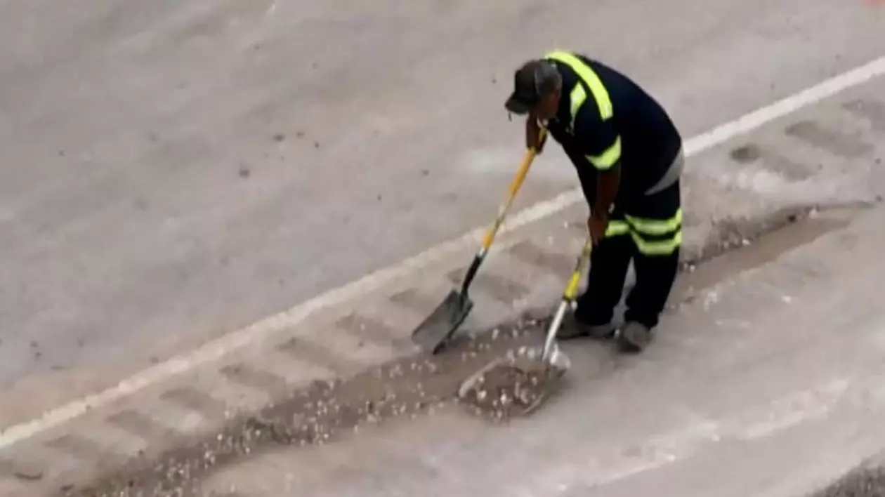 Un pompier strânge cu mătura și fărașul monede de 10 cenți împrăștiate pe o autostradă din Texas, după ce un TIR cu bani s-a răsturnat.
