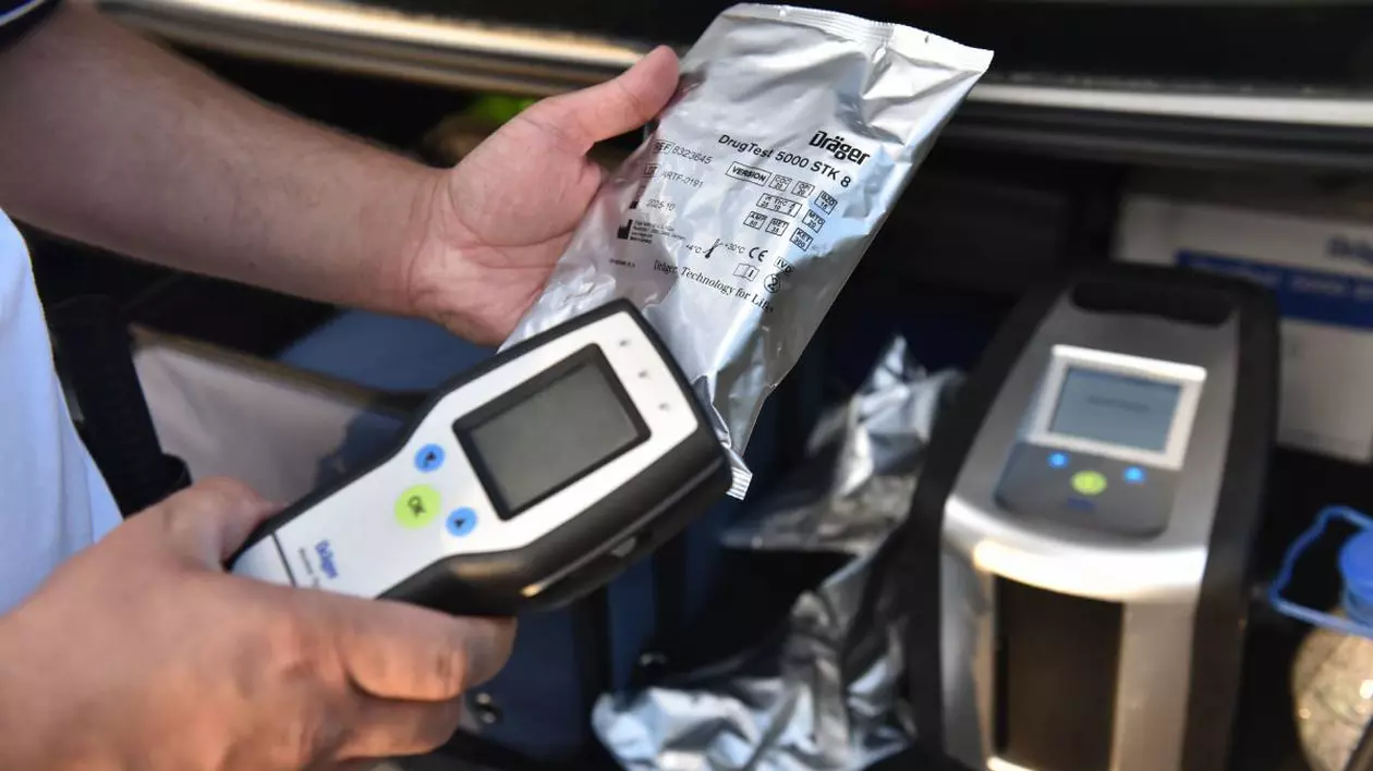 politist care tine in mana un aparat antidrog, pe fundal se observa aparaturl drogtest