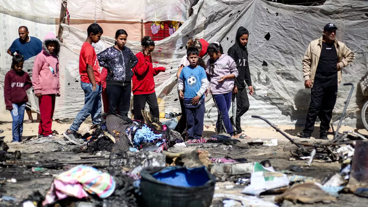 Copiii se adună lângă rămășițele unui adăpost de corturi care ar fi fost lovit de un atac israelian în Khan Yunis, în sudul Fâșiei Gaza, pe 17 aprilie 2025