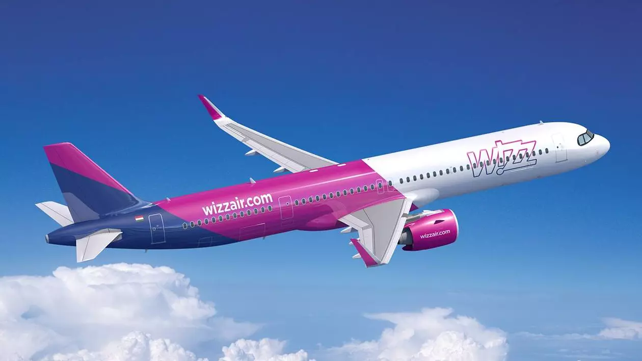 avion care apartine companiei wizz air, modelul Airbus A321neo. fuselajul este vopsit în culorile specifice companiei: roz, violet și alb.