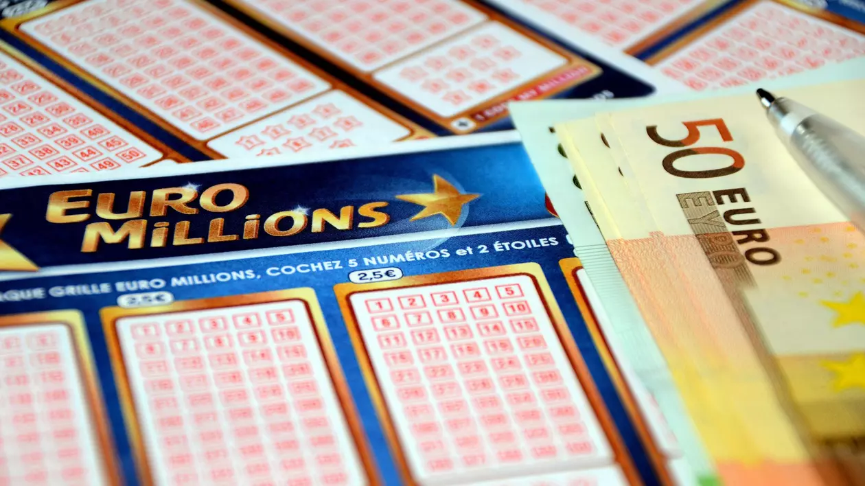 Poză cu un bilet EuroMillions, iar lângă se află bancnote de 50 de euro și un pix