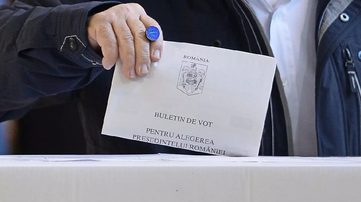 O mânâ de bărbat ține un buletin de vot pentru alegrea presedintelui României și o ștampilă de vot, deasupra unei urne. O persoana isi exercita dreptul la vot in cadrul alegerilor prezidentiale, la Liceul Jean Monnet din Capitala, duminica, 10 noiembrie 2019.