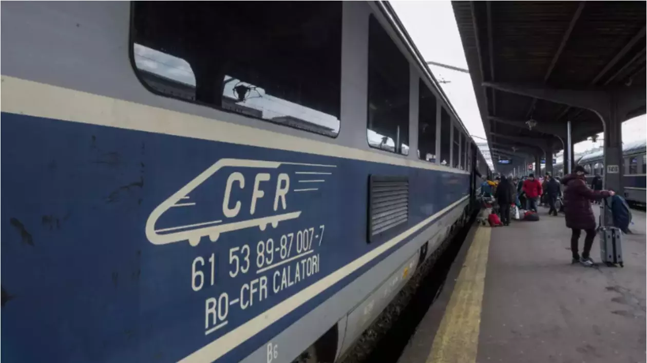 În imagine este ilustrat un tren CFR într-o gară. Pe peron se află mai mulți oameni îmbrăcați cu geci