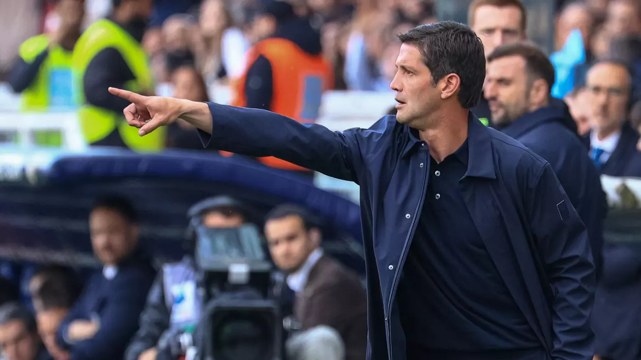 Cristi Chivu, într-o tribună din Parma, Italia, alături de mai mulți suporteri, în timpul unui meci de fotbal. Este îmbrăcat cu o bluză neagră, peste care are o cămașă desfăcută, bleumarin, și arată cu degetul spre teren.