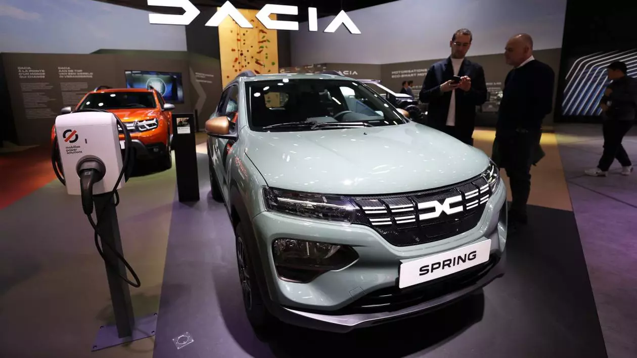 masina electrica dacia spring expusa intr-un showroom. in jurul masinii sunt cateva persoane care studiaza automobilul