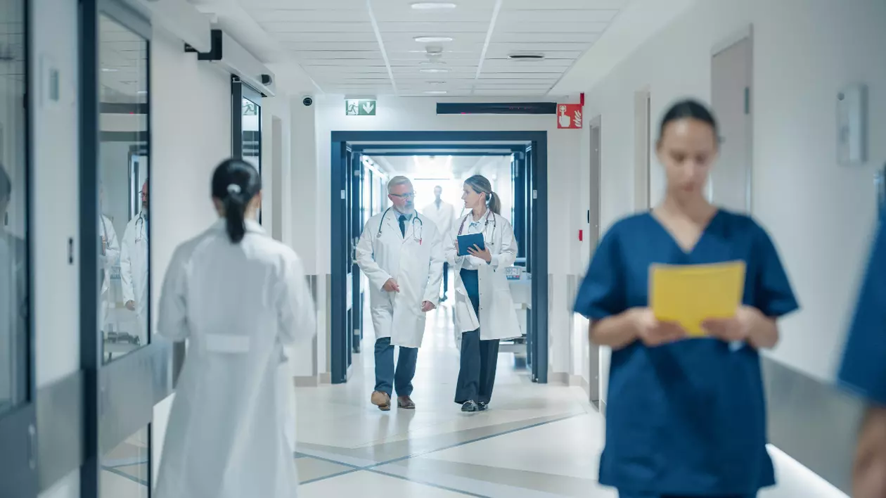 În imagine sunt ilustrați doctori și asistente, pe coridorul spitalului