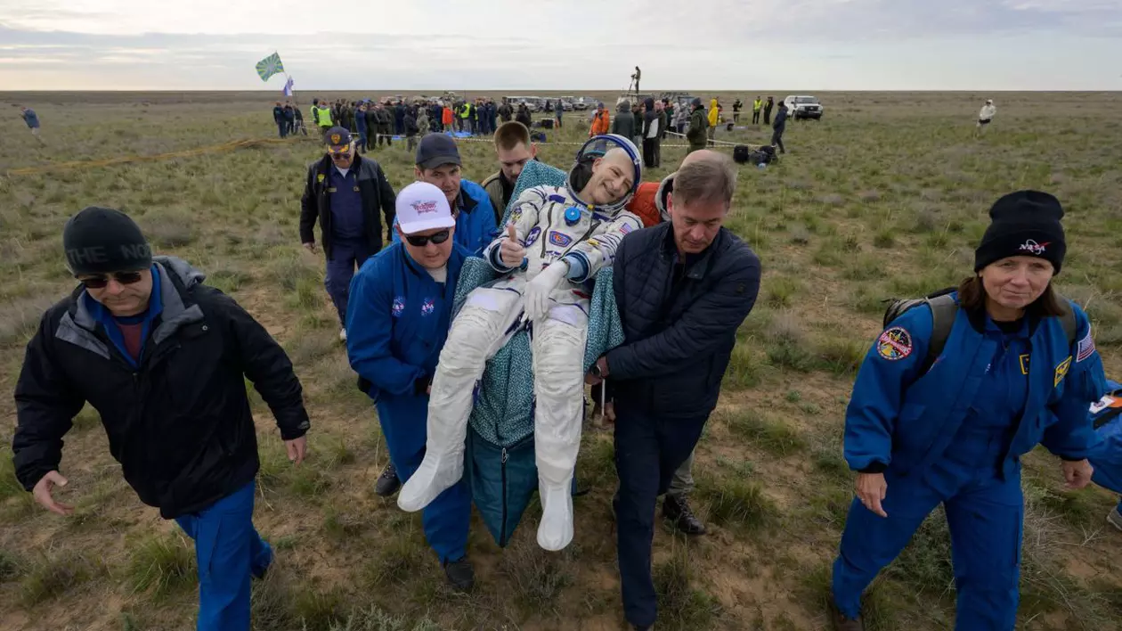 Astronautul NASA Don Pettit face semn că este ok în timp ce este purtat pe brațe după aterizarea navetei Soyuz MS-26 în Kazahstan.