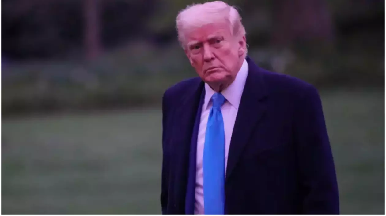 În imagine este ilustrat Donald Trump, care este îmbrăcat într-un costum negru, poartă o cămașă albă și o cravată albastră