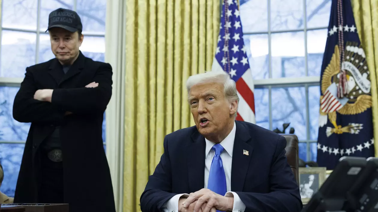 Donald Trump pozat în Biroul Oval, iar în spatele lui se alfă Elon Musk