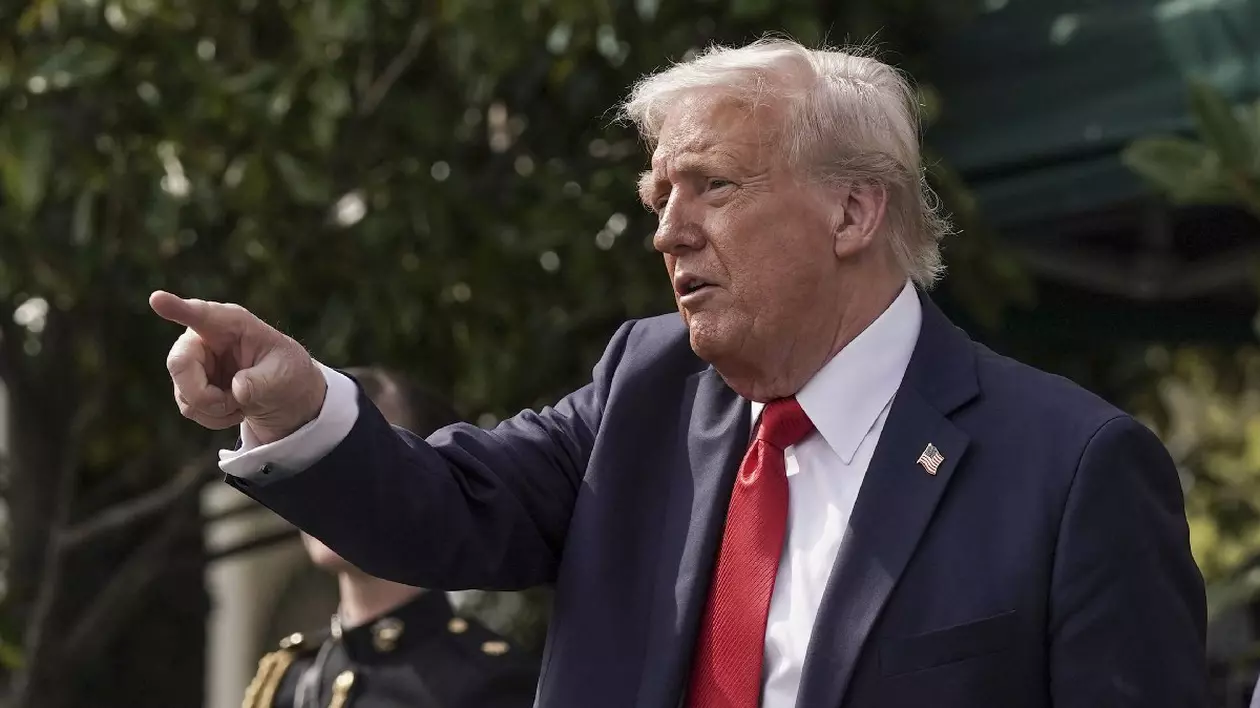 Donald Trump arată cu degetul spre mulțime, imbracat în costum ablastru, cravata rosie si camasa alba