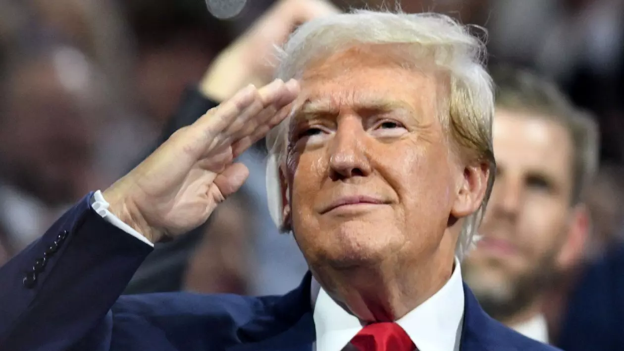 Donald Trump cu mâna la cap, în semn de respect, bandajat la urechea dreaptă. Trump a venit la Convenția Națională Republicană la Fiserv Forum în Milwaukee, Wisconsin luni 15 iulie 2024 la sfârșitul primei zile a convenției. Urechea dreaptă a lui TRUMP este bandajată după ce a fost zgâriată în timpul tentativei de asasinat de sâmbătă. El a fost nominalizat oficial în timpul sesiunii de după-amiază. Fiul său ERIC TRUMP este în spatele său.