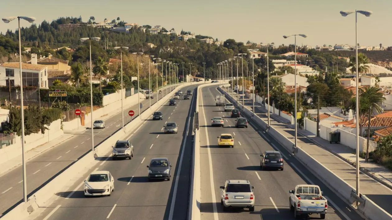 Autostradă din Malaga, Spania, văzută de sus, cu mai multe mașini. Fotografia are o ușoară tentă gălbuie.