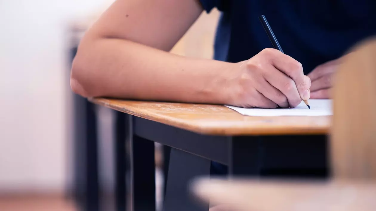 Elev surprins cu un creion în mână, în timpul unui examen.