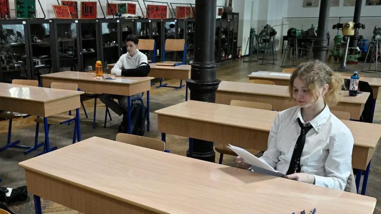 Elevă care stă în bancă la școală și citește lucrarea primită la examen
