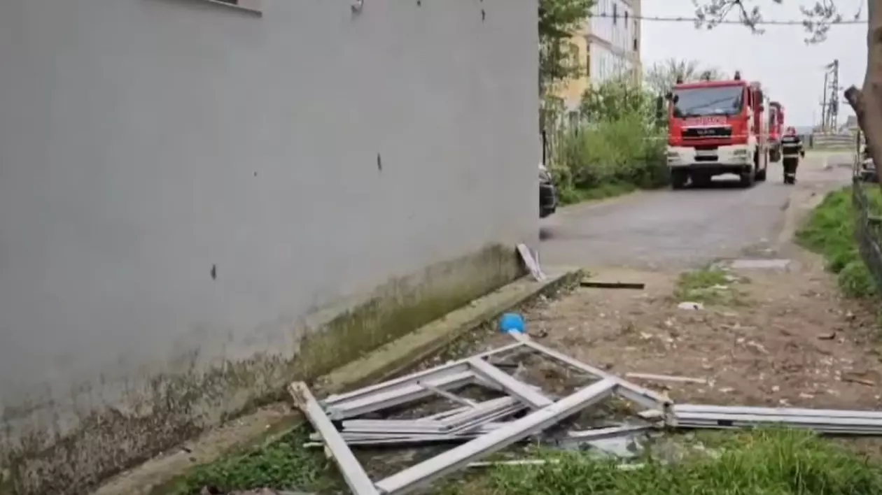 Explozie la un bloc, resturi pe jos, in fundal se vede un echipaj de intervenție al pompierilor