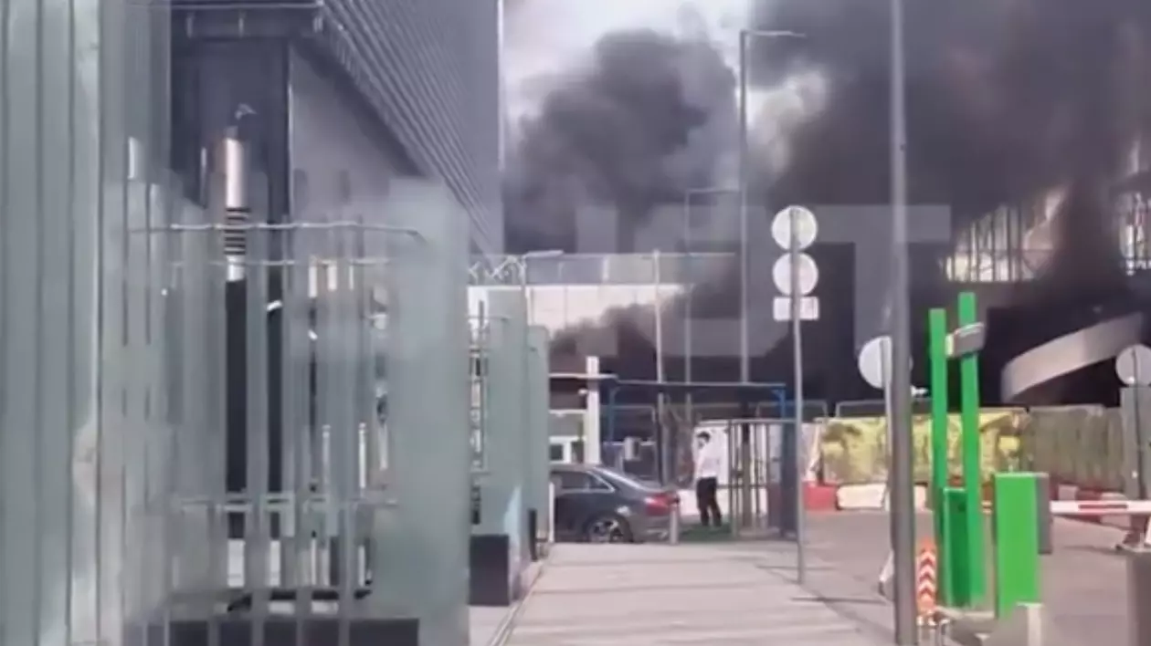 În imagine este ilustrată o parcare în care se observă fum negru, în urma unui incendiu