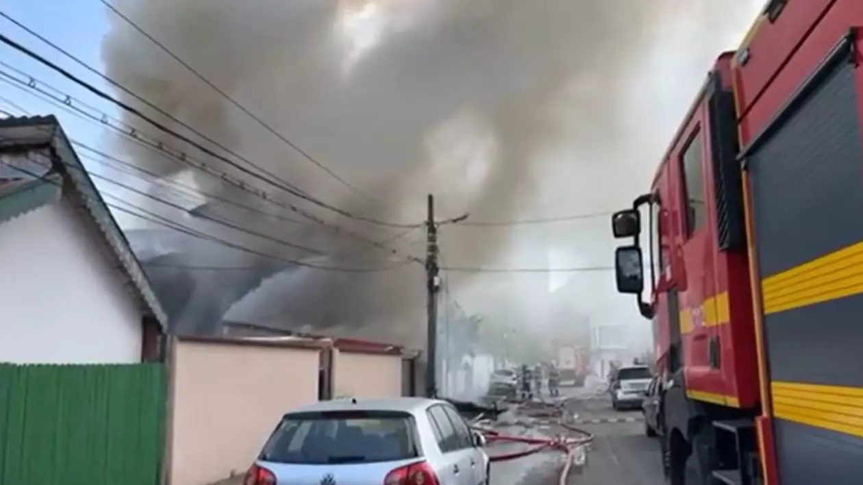 in imagine se observa o masina d epompieri care intervine la un incediu major in Bucuresti. In fundal se observa o coloana mare de fum care se ridica la cer