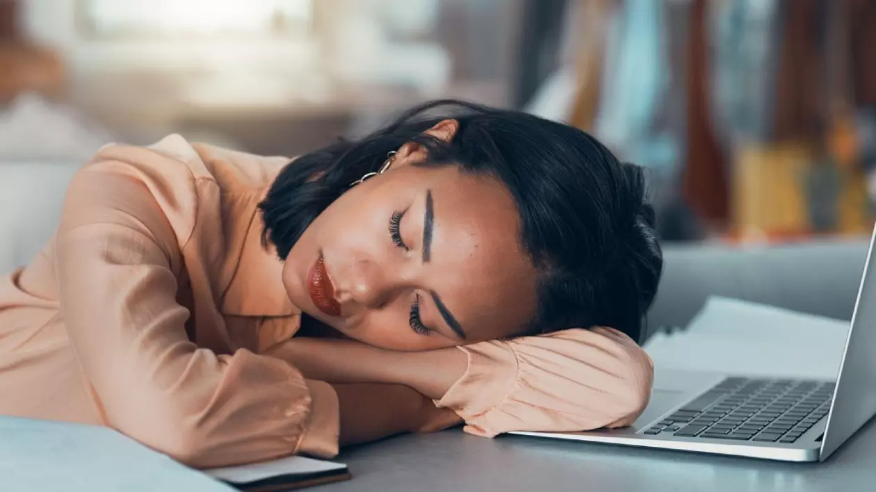 femeie obosită care doarme la job cu capul pe laptop