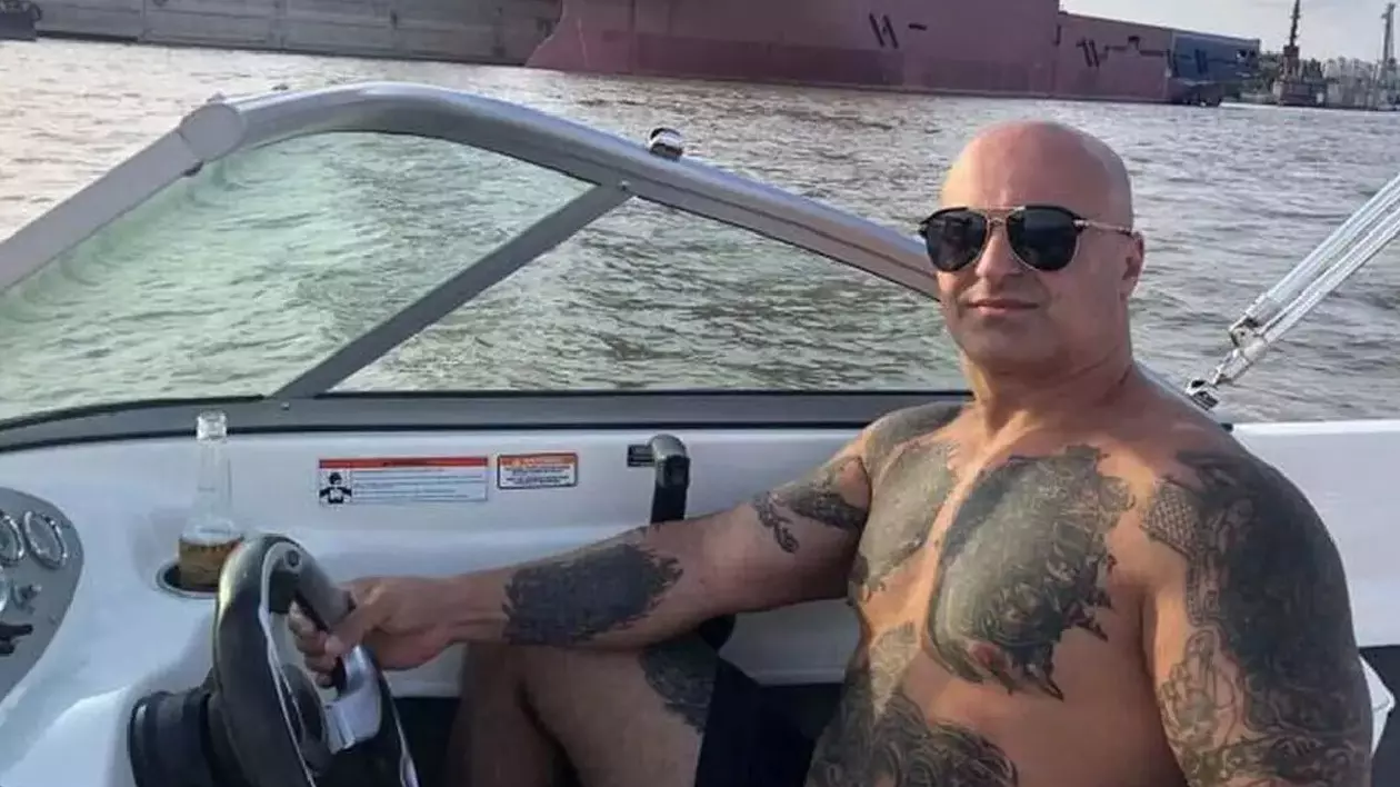 Un bărbat chel, tatuat, cu ochelari de soare, într-o barcă