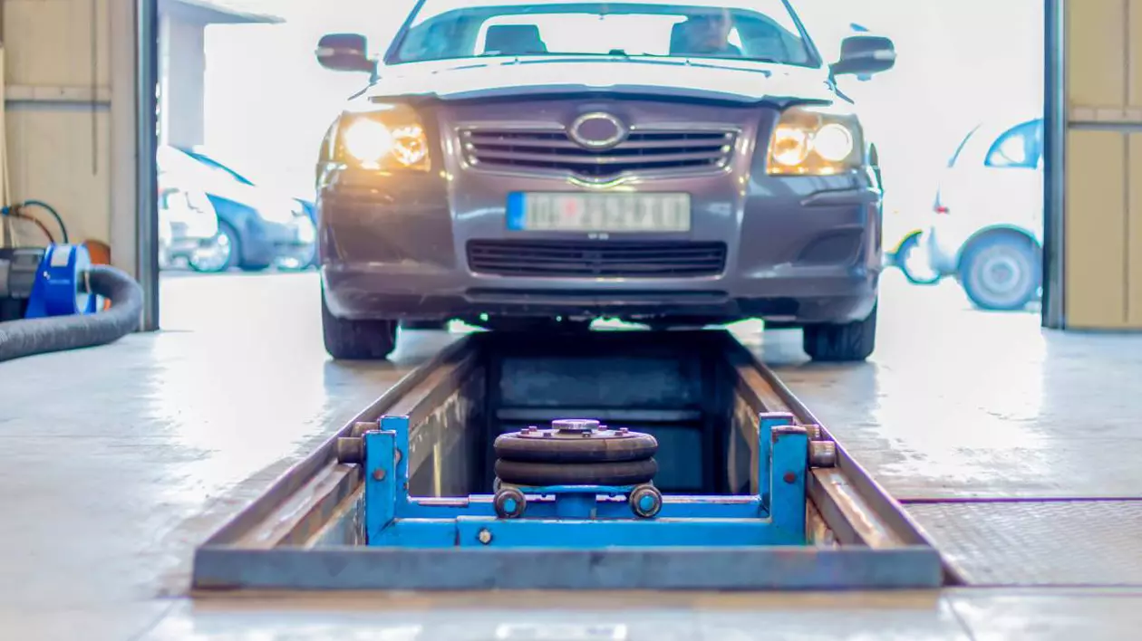 Mașină de culoare gri într-o stație ITP, poziționată deasupra unei rampe de inspecție, specifică atelierelor auto.