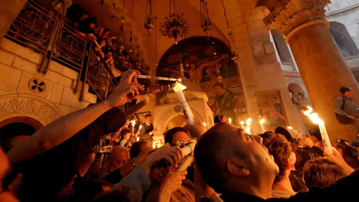 Credinciosi in biserica cu lumânări aprinse iau lumina Sfantă de PAște