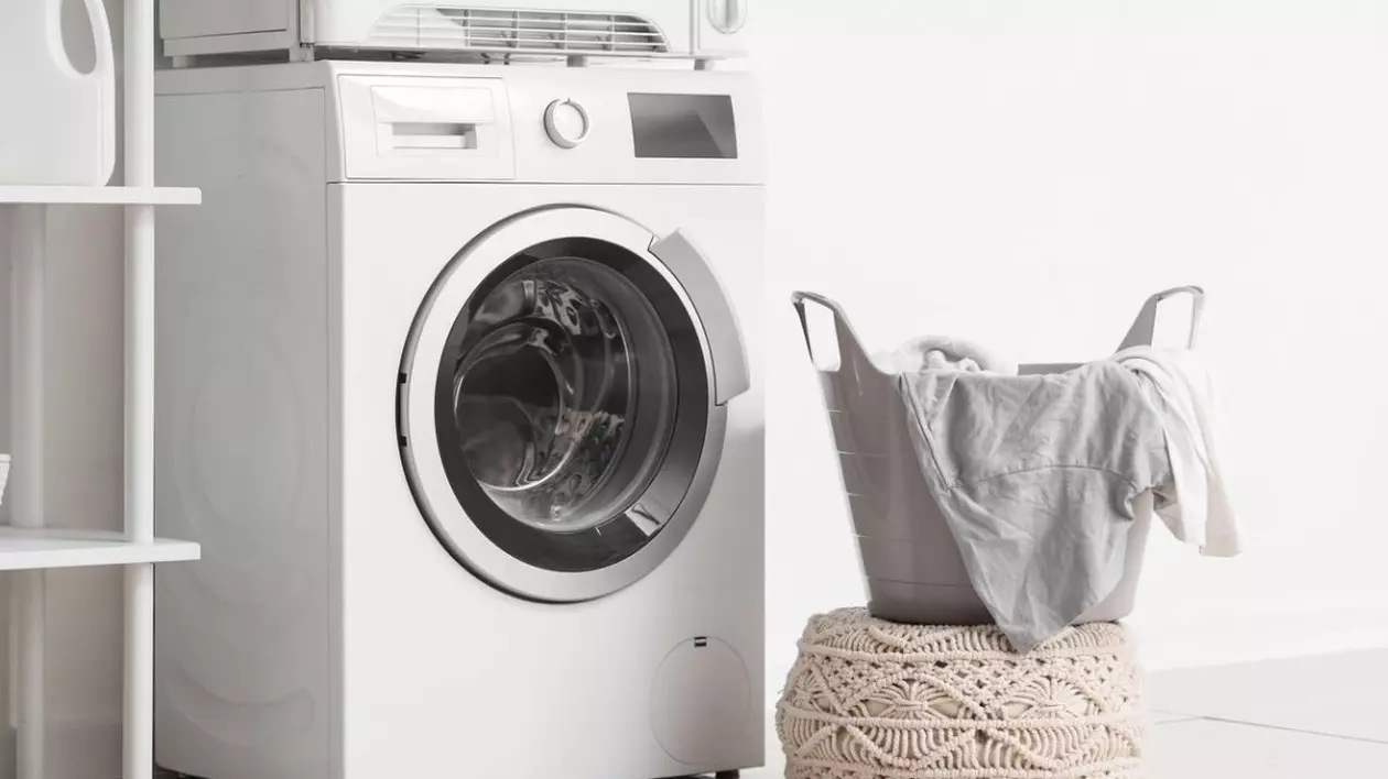 Interiorul spălătoriei cu mașină de spălat modernă și uscător de rufe lângă peretele alb