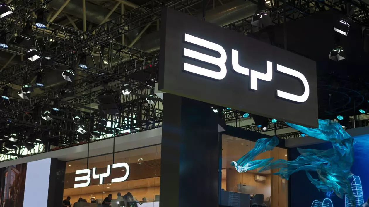 Stand de expoziție al companiei BYD. Logo-ul BYD este vizibil atât pe panoul suspendat central, cât și pe fațada standului.