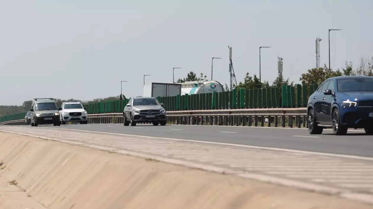 Mai multe mașini circulând pe Autostrada Soarelui cu două benzi pe sens. Cele două sensuri sunt separate de un parapet.