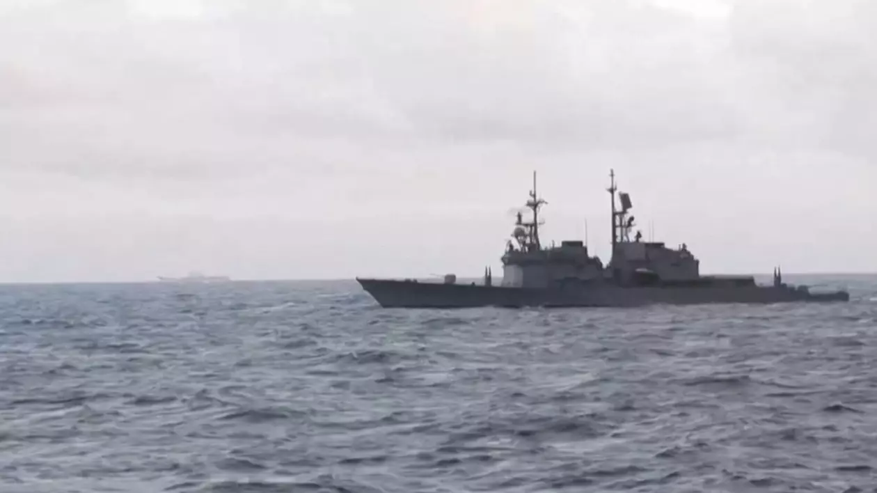 Imaginea arată o navă militară care navighează pe o mare agitată sub un cer înnorat.