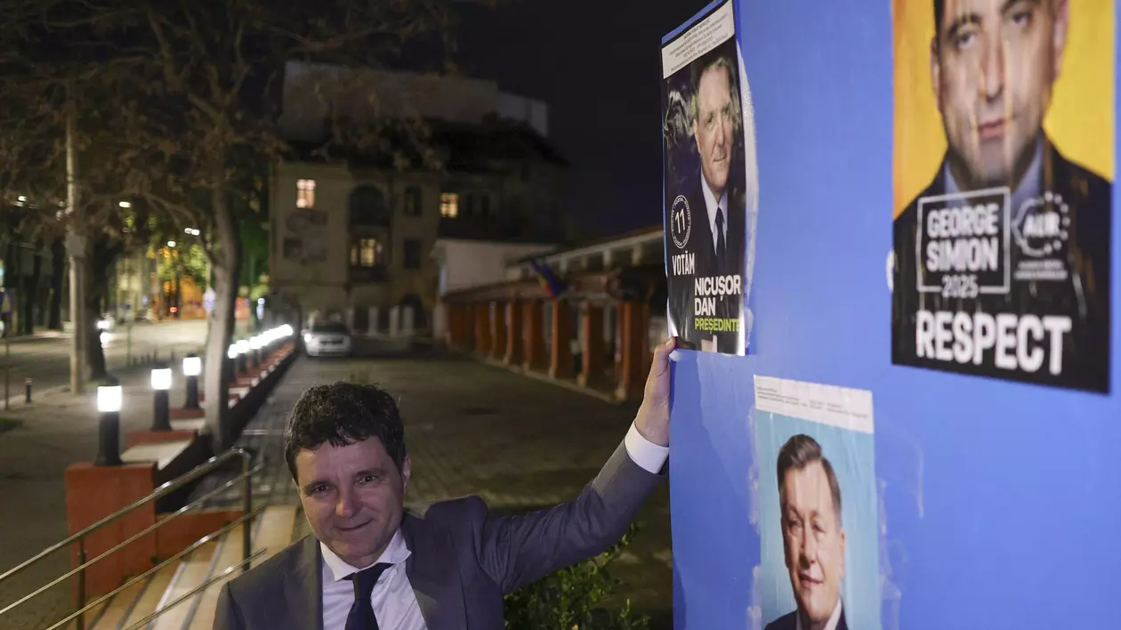 Nicusor Dan langa un panou cu afisaj electoral unde se vede afisul sau de campanie, dar si al lui Crin Antonescu si George Simion