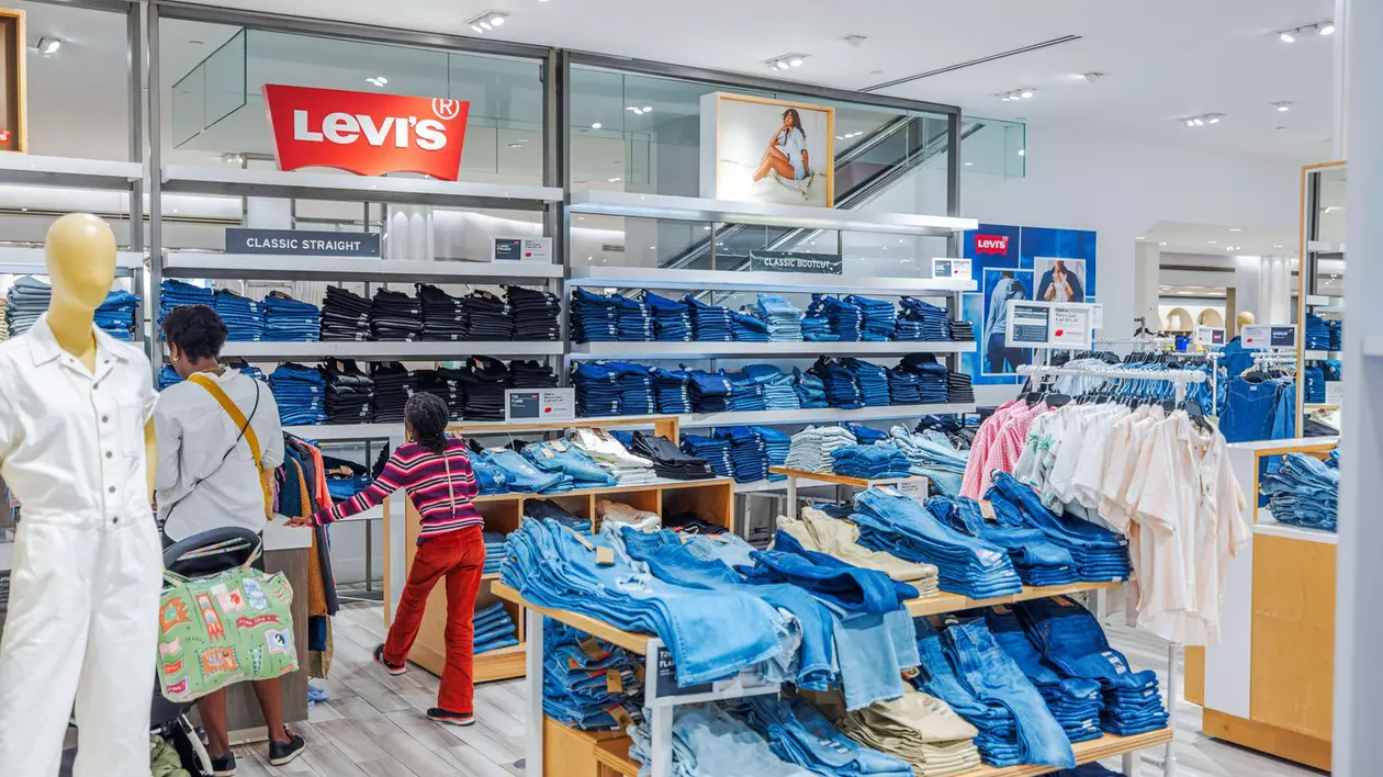 Oameni la cumpărături pentru Levi's denim la magazinul Macy's în secțiunea de vânzare cu amănuntul spațioasă și luminoasă cu blugi stivuiți. New York. SUA.
