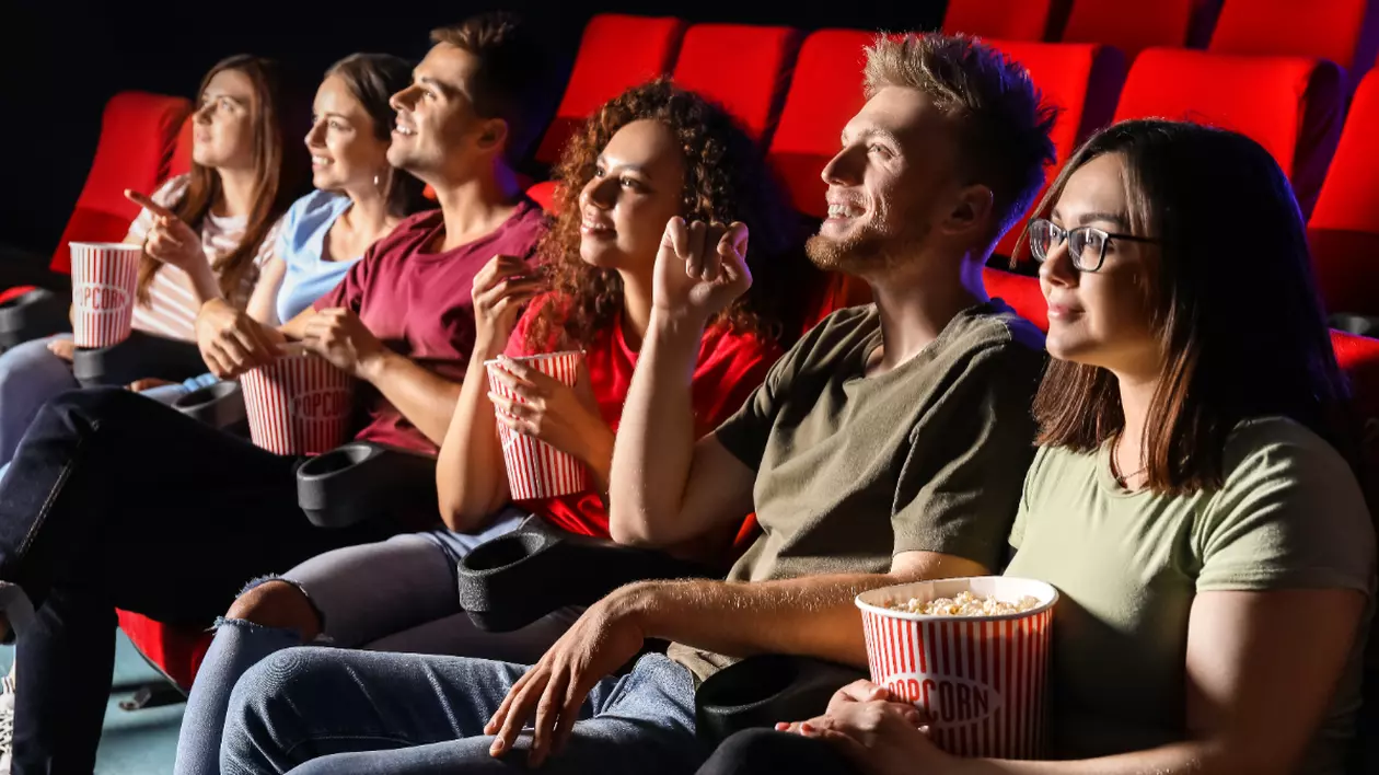În imagine sunt ilustrați oameni care se află la cinema. Aceștia mănâncă popcorn și se uită la film