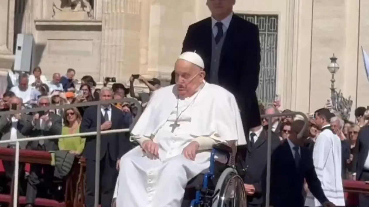 Papa Francisc in scaun cu rotile, impins de un bărbat, în multime
