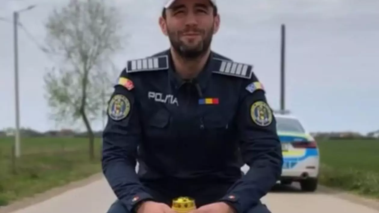 Poză cu polițistul care a transmis un mesaj din partea MAI stând pe un scaun, în mijlocul drumului, și având în mâini o candelă